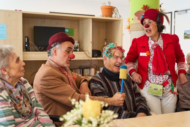Zwei Clowns zu Besuch bei Bewohnerinnen und Bewohnern am Tisch